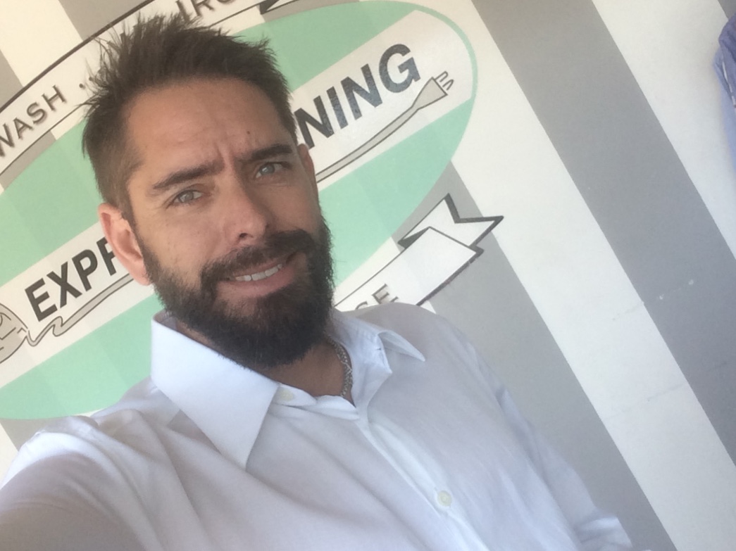 A member of the Express Ironing team outside the shop, in front of the storefront sign
